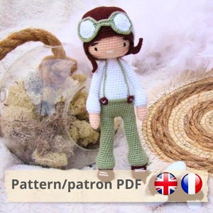 Peut inclure: Patron de poupée amigurumi au crochet en format PDF. La poupée porte une chemise blanche, un pantalon vert et des lunettes d'aviateur. Le patron est disponible en anglais et en français.