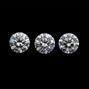 May include: Three round-cut diamonds, each with multiple facets, sparkle against a black background. The diamonds are clear and reflect light, showcasing their brilliance. The image highlights the clarity and cut of the gemstones.