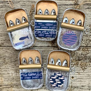 "Die ""Blaue Sammlung"" Dose mit Sardinenfischen, die Metalldosendekorationsbügel-Küstendekor-Geschenk hängen."