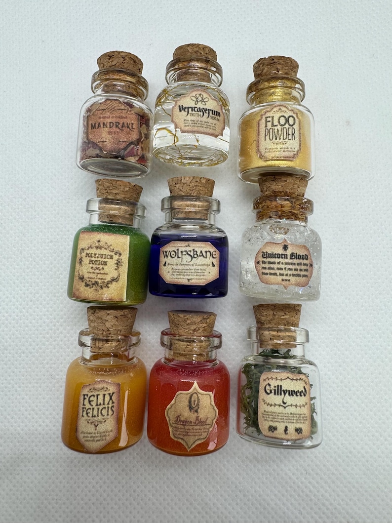 May include: Nine small glass potion bottles with cork stoppers. Each bottle contains a different colored liquid or substance and has a label with a unique name, such as "Mandrake" and "Felix Felicis". The bottles are arranged in three rows of three.