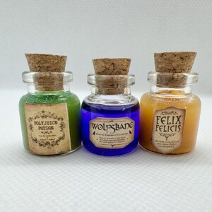 May include: Three small glass potion bottles with cork stoppers. The bottles contain green, blue, and orange liquids. Each bottle has a label with text: "Polyjuice Potion", "Wolfsbane", and "Felix Felicis".