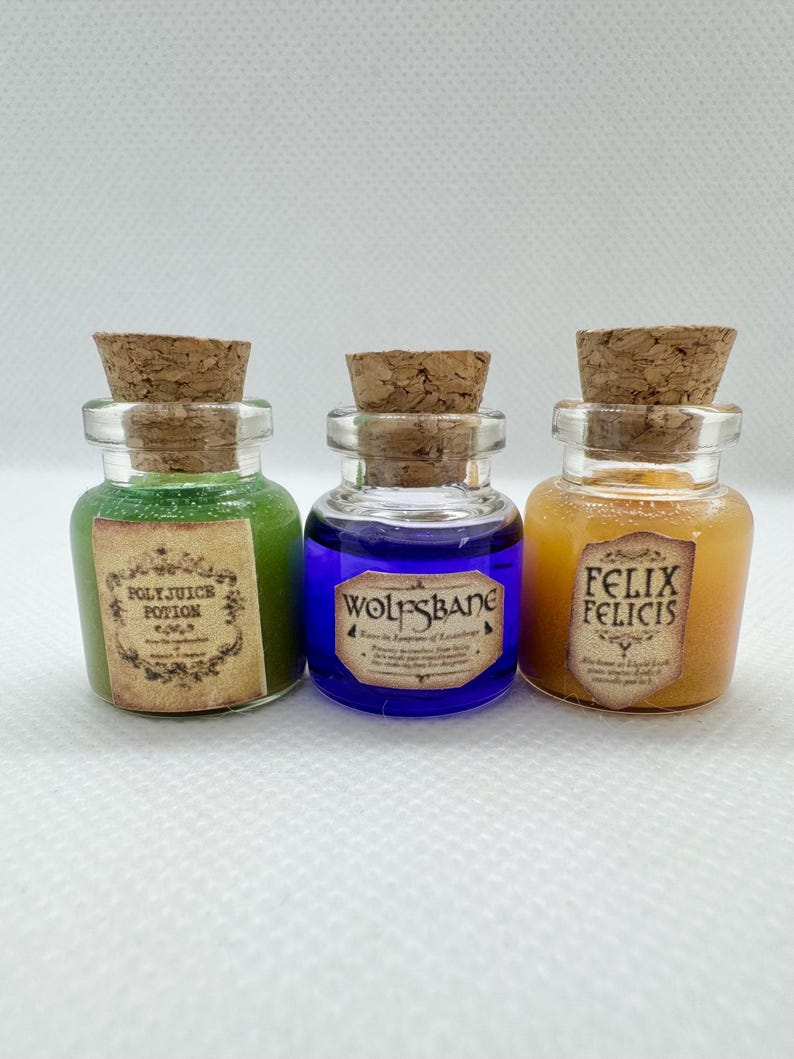 May include: Three small glass potion bottles with cork stoppers. The bottles contain green, blue, and orange liquids. Each bottle has a label with text: "Polyjuice Potion", "Wolfsbane", and "Felix Felicis".