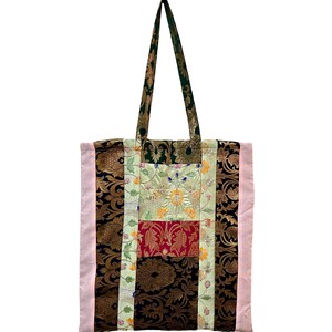 May include: A patchwork tote bag with a variety of patterned fabrics. The bag features a combination of floral, paisley, and solid fabrics in shades of green, red, gold, black, and pink. The handles are green and gold.