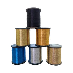 Pode incluir: Uma pirâmide de sete bobinas de fio metálico em várias cores. As cores incluem preto, dourado, bronze, azul e prata. As bobinas são cilíndricas com bordas pretas e são empilhadas umas sobre as outras.