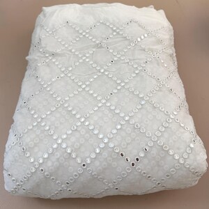 May include: White fabric with a diamond pattern of small, reflective embellishments. The fabric appears soft and slightly translucent, with the embellishments catching the light. The overall effect is delicate and decorative.
