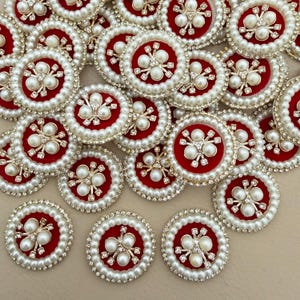 May include: A collection of circular patches featuring a deep red velvet center adorned with three white faux pearls and small clear crystals. Each patch is bordered by a double row of white faux pearls and a thin outer rim of clear crystals.