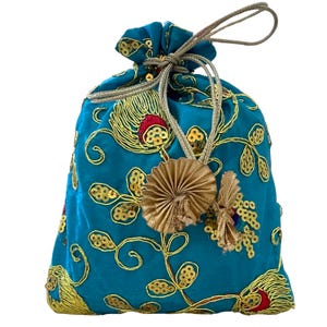 May include: A teal drawstring bag with gold embroidery and sequins. The bag features a floral design with red accents and a gold tassel. The drawstring is a gold-colored cord. The bag is closed at the top.