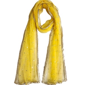 May include: A yellow sheer scarf with a gold trim and sequins. The scarf is folded in half and has a loop at the top.