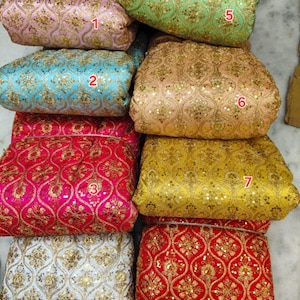 May include: Eight folded fabric swatches featuring a repeating gold embroidered ogee pattern with sequins. The colors include pink, light green, light blue, peach, bright pink, yellow, white, and red, each labeled with a red number from one to eight.