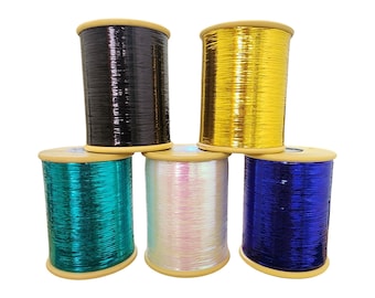 Puede incluir: Cinco carretes de hilo metálico en varios colores: negro, dorado, turquesa, blanco iridiscente y azul. Cada carrete es cilíndrico con una base y tapa de madera. El hilo tiene una calidad brillante y reflectante, ideal para proyectos de manualidades y embellecimiento.