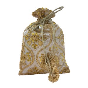 Puede incluir: Bolsa con cordón y bordados dorados y lentejuelas. La tela blanquecina está adornada con patrones florales y arremolinados. Se ata con un cordón y borla dorados, creando un accesorio elegante y decorativo.