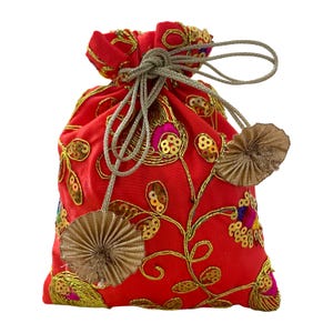 Peut inclure: Un petit sac rouge à cordon avec broderies et sequins dorés. Le sac présente un motif floral avec du fil et des sequins dorés, et est noué avec un cordon gris argenté. Deux glands décoratifs dorés en forme d'éventail pendent du sac.