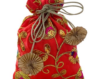 Può includere: Un sacchetto rosso con coulisse, ricami dorati e paillettes. Il sacchetto presenta un motivo floreale con filo d'oro e paillettes, ed è legato con un cordoncino grigio argento. Due nappe decorative dorate a forma di ventaglio pendono dal sacchetto.