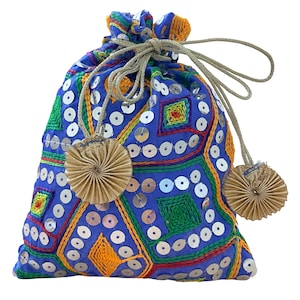 Op de afbeelding: Een blauwe trekkoordtas met ingewikkelde borduursels en pailletten. De tas heeft kleurrijke geometrische patronen in groen, oranje en geel. Hij heeft een gouden trekkoord en twee decoratieve gouden waaiervormige kwastjes.
