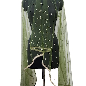 May include: A green sheer scarf with gold polka dots and a gold trim. The scarf is draped over a black dress form.
