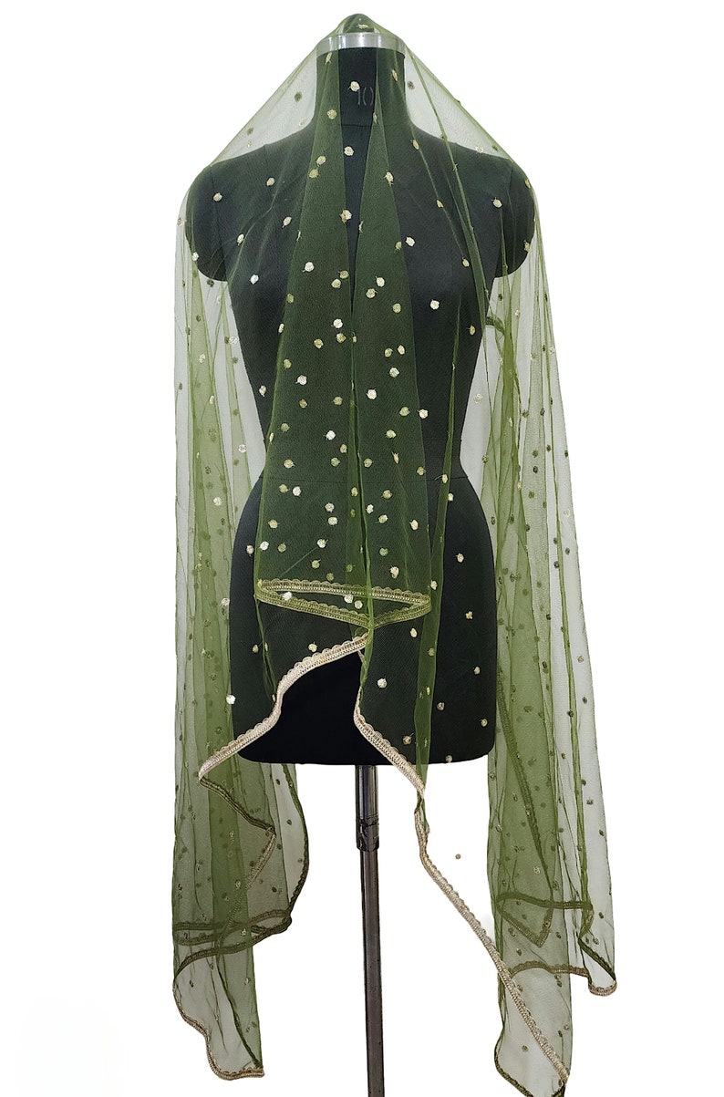 May include: A green sheer scarf with gold polka dots and a gold trim. The scarf is draped over a black dress form.