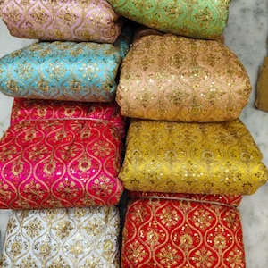 May include: A collection of folded fabric pieces in various colors including pink, green, blue, peach, yellow, red, and white. Each piece features a repeating gold embroidered lattice pattern with floral motifs and small reflective sequins throughout.