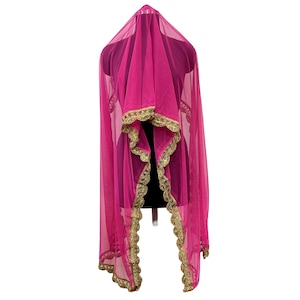 May include: A vibrant pink sheer veil with gold trim, displayed on a mannequin. The veil is draped to showcase its flowing design and intricate gold detailing along the edges, creating an elegant look.