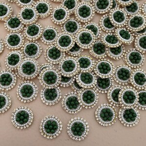 Op de afbeelding: Een verzameling decoratieve versieringen. Elk cirkelvormig stuk heeft een centrale cluster van donkergroene kralen, omgeven door een ring van witte parels en een goudkleurige rand. De buitenrand is afgezet met heldere strass-steentjes.