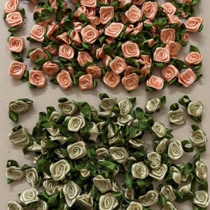 Könnte beinhalten: Eine Sammlung kleiner Rosenverzierungen aus Stoff in zwei Farbschemata. Der obere Bereich zeigt pfirsichfarbene Rosen mit grünen Blättern, während der untere Bereich cremefarbene Rosen mit grünen Blättern zeigt. Ideal für Bastelprojekte.