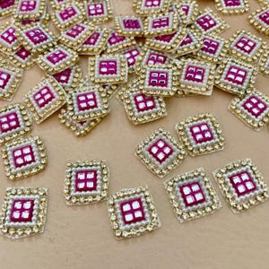 May include: Scattered square embellishments with a gold border, white pearls, and a magenta centre. These decorative pieces are ideal for craft projects, with their intricate design and eye-catching colours.