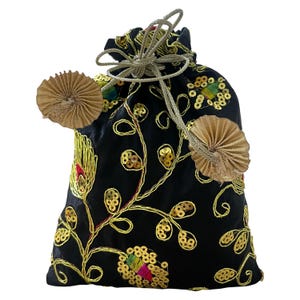 Może przedstawiać: Czarny worek ze sznurkiem, ze złotym haftem kwiatowym i akcentami z cekinów. Torba posiada złote zamknięcie na sznurek i dwie dekoracyjne złote chwosty w kształcie wachlarza. Haft zawiera czerwone, zielone i żółte detale.