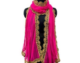 May include: A vibrant pink scarf with intricate gold-colored trim and detailing. The scarf is draped over a black mannequin, showcasing its flowing design and decorative edges. The scarf's fabric appears sheer and lightweight.