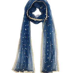 May include: A blue sheer scarf with gold trim and white sequins. The scarf is folded in half and draped over a white background.