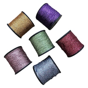 May include: Six spools of glitter thread in gold, purple, green, red, pink, and blue. Each spool is wound on a black plastic core, suitable for crafting and embellishments.