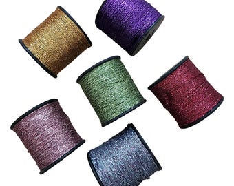 Puede incluir: Seis carretes de hilo con purpurina en varios colores: dorado, morado, verde, rojo, rosa y azul. Cada carrete está enrollado en un núcleo de plástico negro, ideal para manualidades.