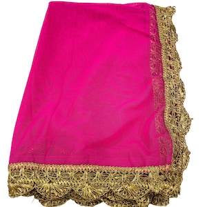 May include: A vibrant fuchsia-colored sheer fabric with a decorative gold trim. The trim features an intricate, repeating floral pattern along the edges. The fabric is folded, showcasing its texture and color.