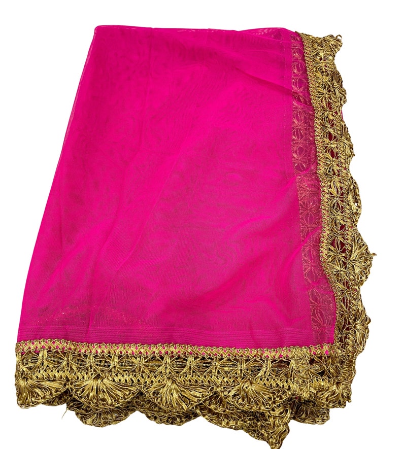 May include: A vibrant fuchsia-colored sheer fabric with a decorative gold trim. The trim features an intricate, repeating floral pattern along the edges. The fabric is folded, showcasing its texture and color.
