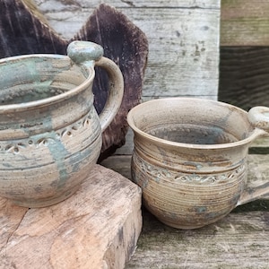 Peut inclure: Deux tasses en céramique faites à la main avec un glaçage rustique et terreux. Les tasses ont un design unique et texturé et sont parfaites pour déguster une boisson chaude.