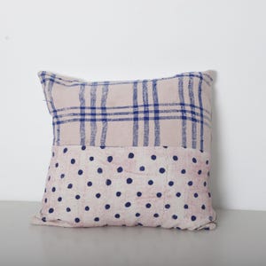 Pode incluir: Uma almofada decorativa quadrada com um design de duas cores. A metade superior apresenta um tecido rosa claro com um padrão xadrez azul, enquanto a metade inferior tem um tecido rosa claro com bolinhas azuis. Para decoração de casa.