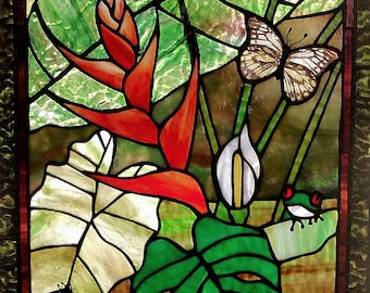 May include: Stained glass panel depicting a tropical scene. Features red flowers, green leaves, butterflies, and a small frog. The artwork is framed with a dark border and showcases vibrant colors and intricate details.