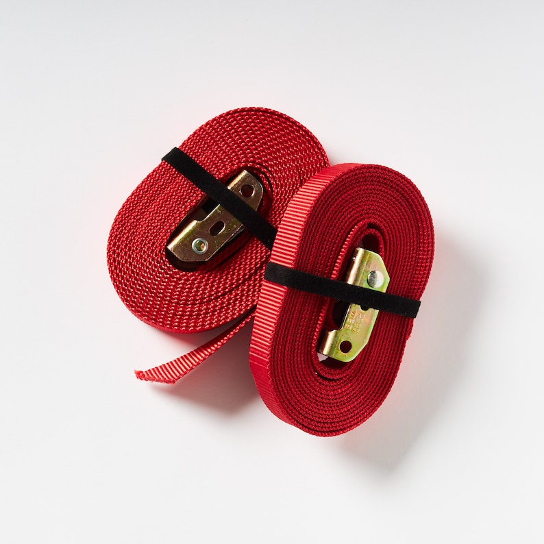 Puede incluir: Dos correas de trinquete rojas con hebillas met&aacute;licas. Las correas est&aacute;n hechas de nylon tejido y tienen una banda el&aacute;stica negra alrededor de cada hebilla.