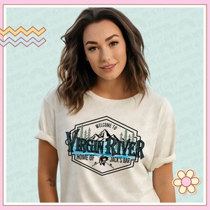 May include: White t-shirt featuring a vintage-style logo design that reads "Welcome to Virgin River, Home of Jack's Bar". The logo includes a mountain range, pine trees, and a fishing lure.