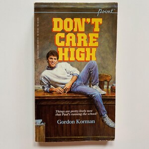 May include: A paperback book titled "DON'T CARE HIGH" with a young man in jeans and a sweater on the cover. The book's title is in large yellow letters with a red outline. The author's name is Gordon Korman.