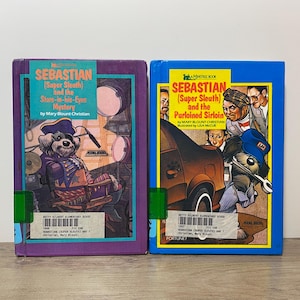 以下が含まれることがあります： 「Sebastian (Super Sleuth)」というタイトルの2冊のヴィンテージ子供向けの本が表示されています。本には、犬の探偵や他のキャラクターのイラストが描かれたカラフルな表紙が付いています。本はベティ・ギルバート小学校のものです。