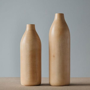 May include: Two wooden vases, one taller than the other, both with a light brown color and a smooth, rounded shape.