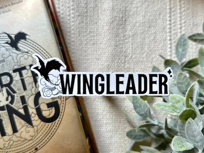May include: Black and white sticker with a flying bird and the text "WINGLEADER" with a small sparkle symbol.