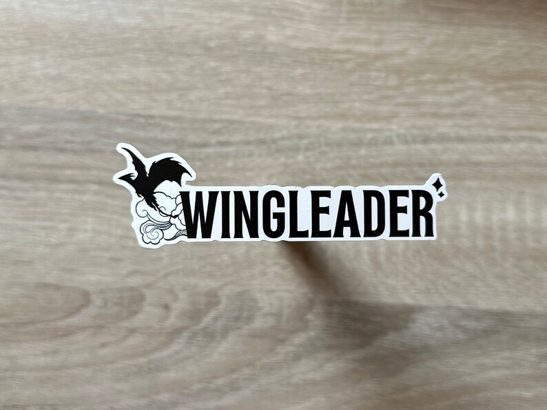 May include: A white sticker with a black silhouette of a bird with wings spread, flying above a cloud. The text "WINGLEADER" is printed in black letters below the bird.