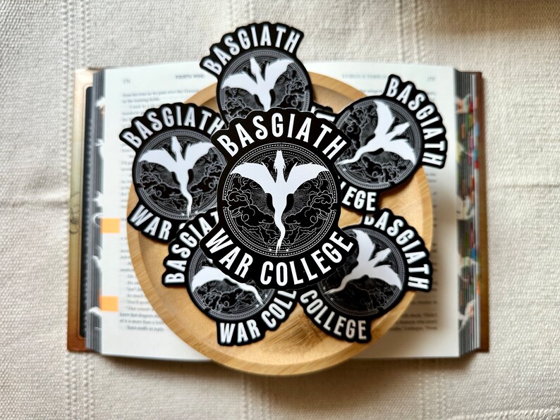 K&ouml;nnte beinhalten: Eine Sammlung von schwarzen und wei&szlig;en runden Aufklebern mit einem Drachenmotiv und dem Text "Basgiath War College".
