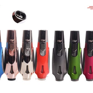 May include: A collection of seven Tesla brand lighters in various colors, including blue, rose gold, silver, red, gray, green, and pink. Each lighter has a black top and a textured grip.