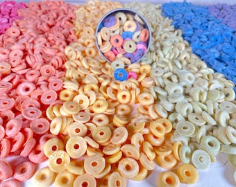 May include: A close-up of a variety of colorful cereal rings. The cereal is arranged in rows of different colors, including pink, yellow, and blue. A small bowl of the cereal is in the center of the image.