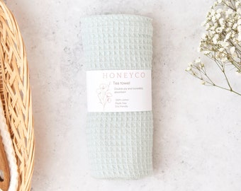May include: A light blue waffle weave tea towel with a white label that reads "Honeyco Tea Towel Double ply and incredibly absorbent 100% cotton Plastic free Eco friendly"