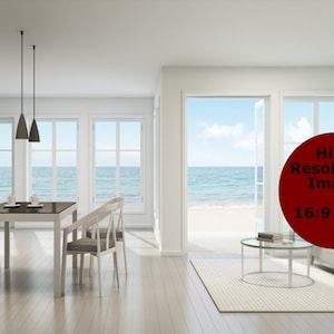 Peut inclure: Une table à manger blanche avec six chaises est installée dans un salon moderne avec de grandes fenêtres donnant sur une plage. La pièce a des murs blancs et un parquet clair. Un canapé gris avec des coussins bleus se trouve dans le salon.