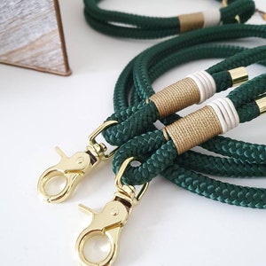 May include: Two green rope dog leashes with gold clasps and white and gold accents.