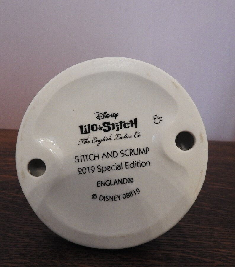 May include: White ceramic figurine base with black text that reads "Disney Lilo & Stitch The English Ladies Co Stitch and Scrump 2019 Special Edition England&reg; &copy; DISNEY 08819".
