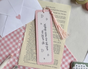 May include: A pink bookmark with a white tassel and the text "The world can wait for one more chapter" in black lettering. The bookmark is decorated with white hearts and a white lace border.